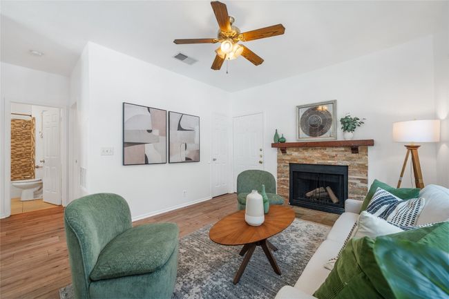 Living room featuring a stone fireplace, wood finished floors, and a ceiling fan | Image 7