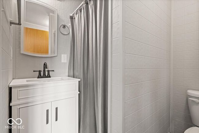 full bathroom featuring tile walls, toilet, vanity, and a shower with curtain | Image 31