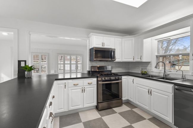 Kitchen offers enameled cabintery, stainless steel appliances, modern subway tile backsplash and laminate flooring | Image 8