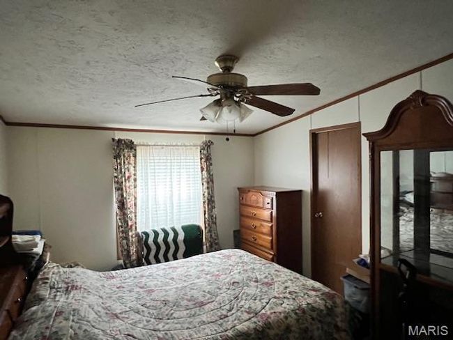 Bedroom with ornamental molding, ceiling fan, and a textured ceiling | Image 6