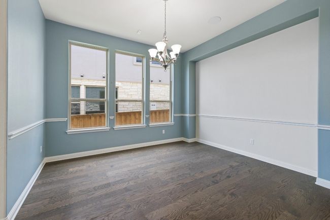Empty room with a chandelier and dark wood finished floors | Image 11