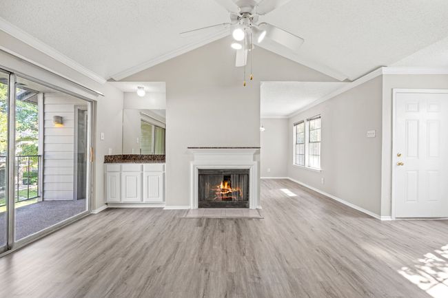 Unfurnished living room with light wood-style flooring, a fireplace with flush hearth, lofted ceiling, and ceiling fan | Image 4