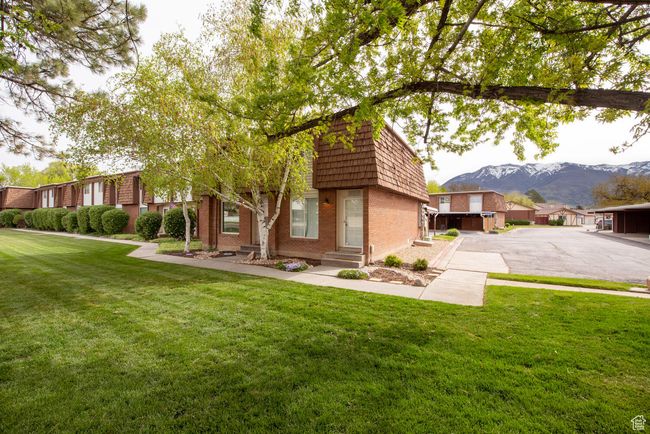 View of front of property with a front yard, a mountain view, brick siding, entry steps, and mansard roof | Image 17