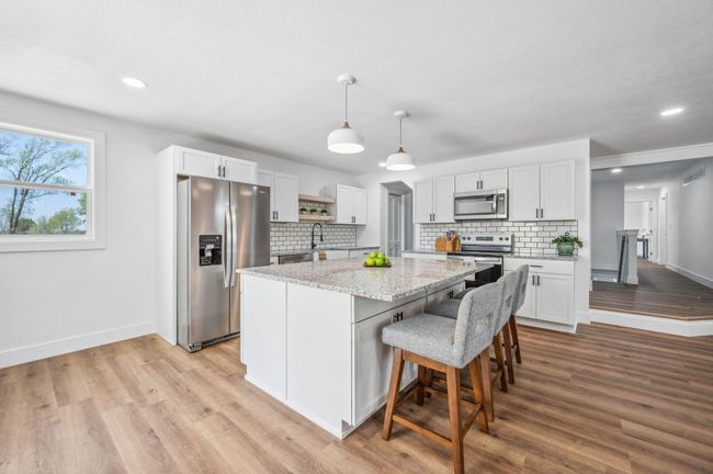 Kitchen featuring tasteful backsplash, baseboards, a kitchen island, light wood-style floors, and stainless steel appliances | Image 9