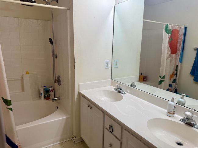 Full bath with shower / bath combo with shower curtain, double vanity, and tile patterned flooring | Image 10