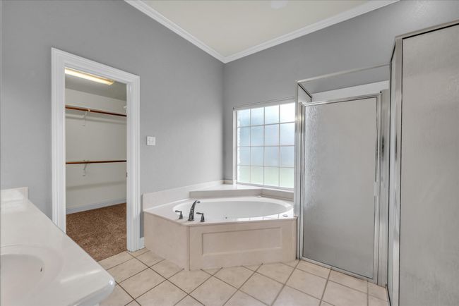 Bathroom with a shower stall, a whirlpool tub, ornamental molding, tile patterned flooring, and a walk in closet | Image 23