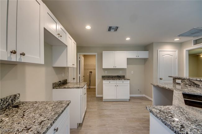 Kitchen with white cabinetry, recessed lighting, visible vents, and light stone countertops | Image 23