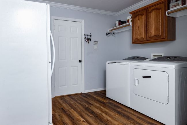 Laundry room featuring dark wood-style floors, crown molding, baseboards, washing machine and clothes dryer, and cabinet space | Image 23