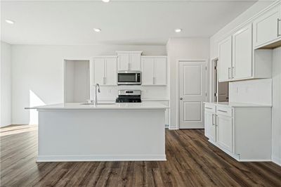 Kitchen featuring dark wood-type flooring, appliances with stainless steel finishes, sink, and a kitchen island with sink | Image 3