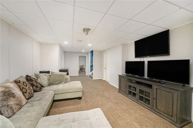 Living room featuring carpet, a drop ceiling, and baseboards | Image 18