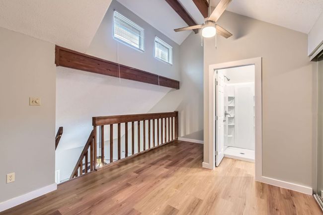 Hallway with baseboards, beamed ceiling, an upstairs landing, wood finished floors, and high vaulted ceiling | Image 14