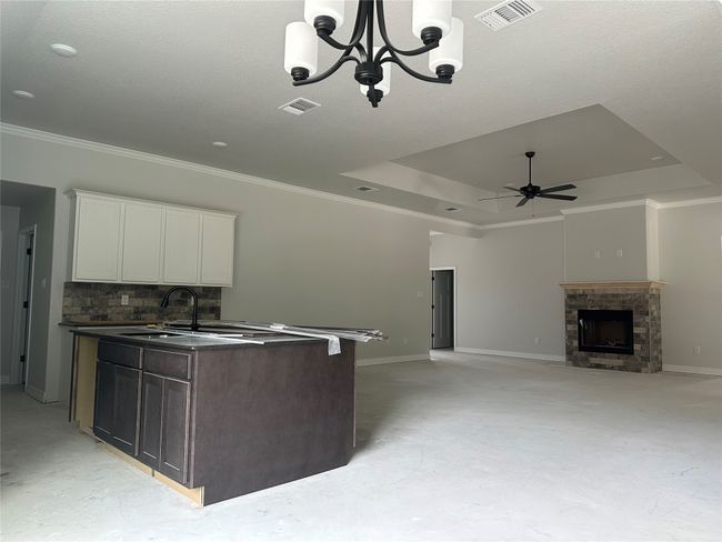 Kitchen featuring a raised ceiling, dark countertops, visible vents, and ceiling fan with notable chandelier | Image 11