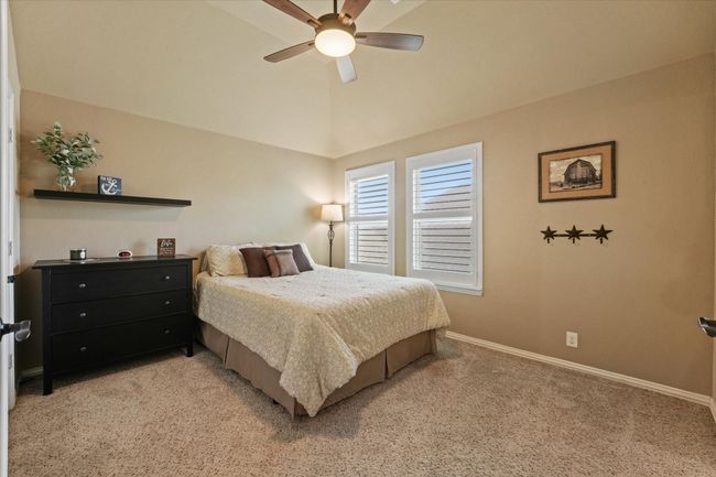Bedroom featuring vaulted ceiling, baseboards, a ceiling fan, and light colored carpet | Image 33
