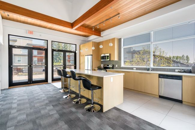 Kitchen featuring rail lighting, appliances with stainless steel finishes, light countertops, a center island, and french doors | Image 26