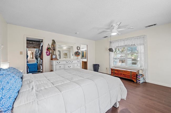 Bedroom with a textured ceiling, visible vents, a ceiling fan, and dark wood-style flooring | Image 16