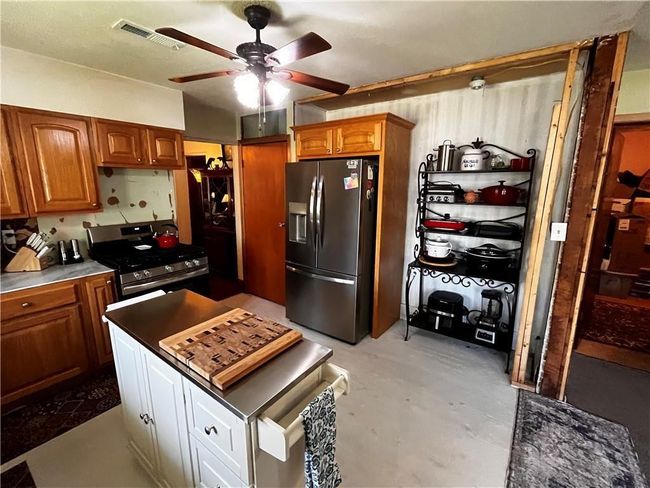 Kitchen featuring appliances with stainless steel finishes, a ceiling fan, brown cabinetry, and concrete floors | Image 8