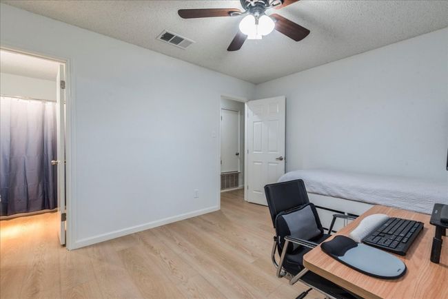 Office space featuring a ceiling fan, a textured ceiling, light wood-style flooring, baseboards, and visible vents | Image 12