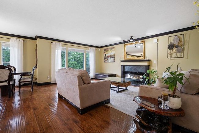 Living area with crown molding, a premium fireplace, dark wood-style flooring, and healthy amount of natural light | Image 6