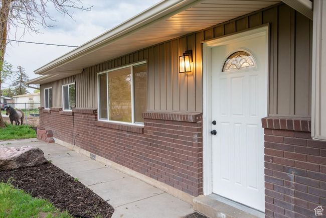 Entrance to property with fence, board and batten siding, and brick siding | Image 4