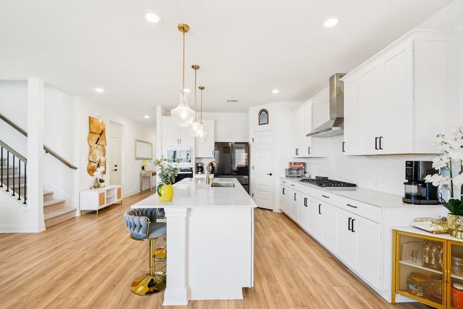 Kitchen with wall chimney range hood, decorative backsplash, light countertops, recessed lighting, and light wood-type flooring | Image 8