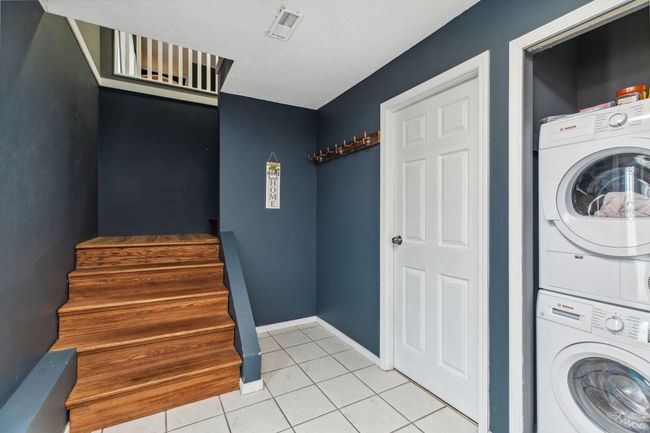 Clothes washing area featuring baseboards, stacked washer and dryer, light tile patterned flooring, visible vents, and laundry area | Image 29
