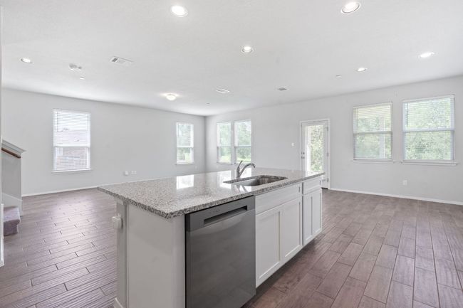 Kitchen featuring stainless steel dishwasher, open floor plan, dark wood-style floors, an island with sink, and recessed lighting | Image 13