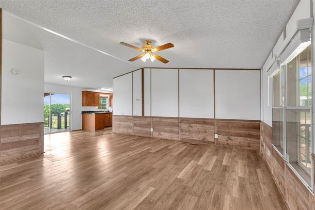 Unfurnished room featuring a ceiling fan, light wood-style flooring, and a textured ceiling | Image 8