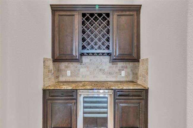 Elevate your entertaining with this sophisticated in-home bar featuring rich cabinetry, granite countertops, built-in wine rack and mini fridge – the perfect spot for evening cocktails or weekend gatherings. | Image 19