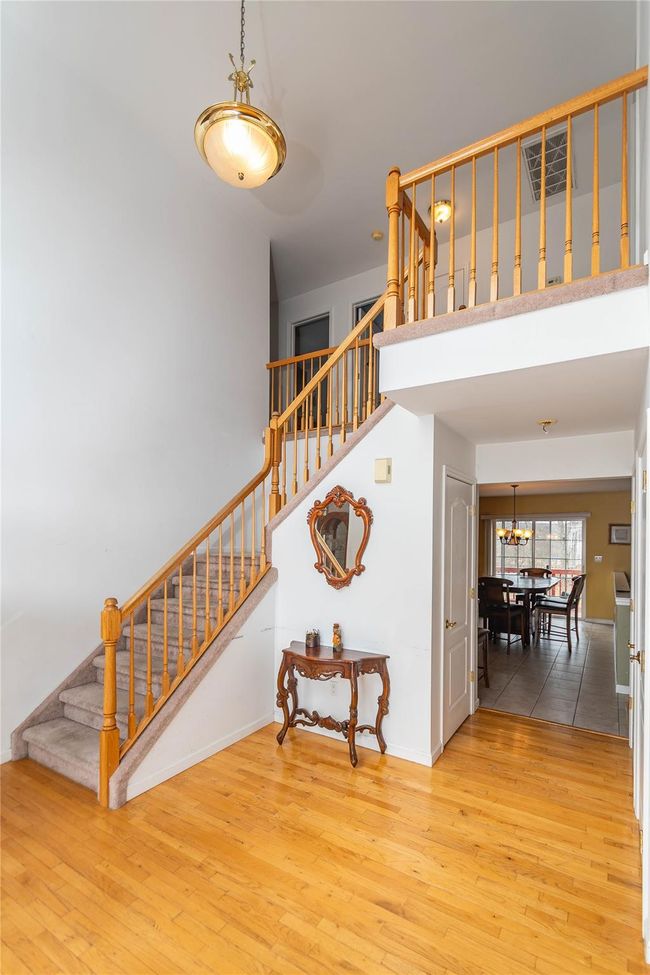 Stairs with wood finished floors, baseboards, visible vents, a towering ceiling, and a chandelier | Image 9