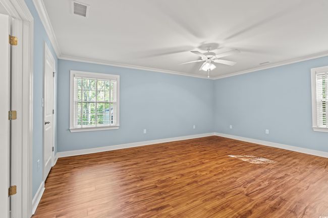 Spare room featuring healthy amount of natural light, a ceiling fan, wood finished floors, and crown molding | Image 11