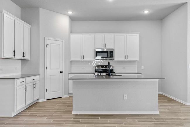 Kitchen with white cabinets, baseboards, appliances with stainless steel finishes, light wood finished floors, and backsplash | Image 5