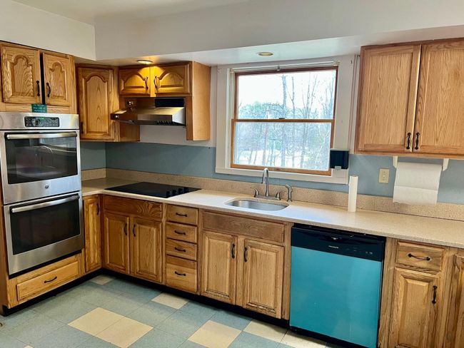 Kitchen with dishwashing machine, under cabinet range hood, a sink, black electric stovetop, and stainless steel double oven | Image 10