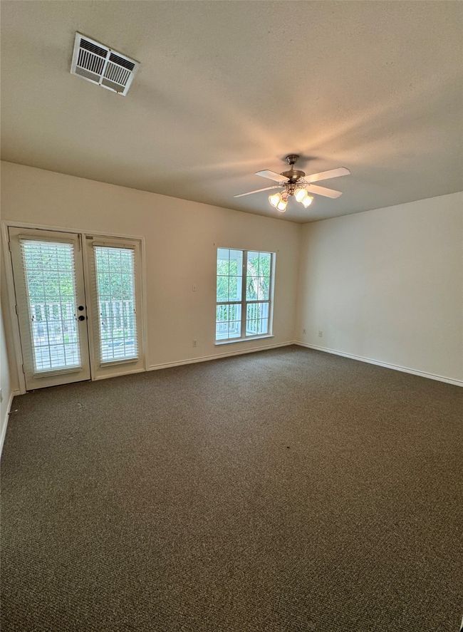 Unfurnished room featuring ceiling fan, baseboards, dark colored carpet, and french doors | Image 12