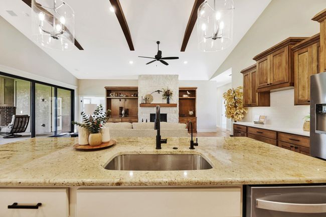 Kitchen featuring light stone counters, sink, hanging light fixtures, and vaulted ceiling | Image 14