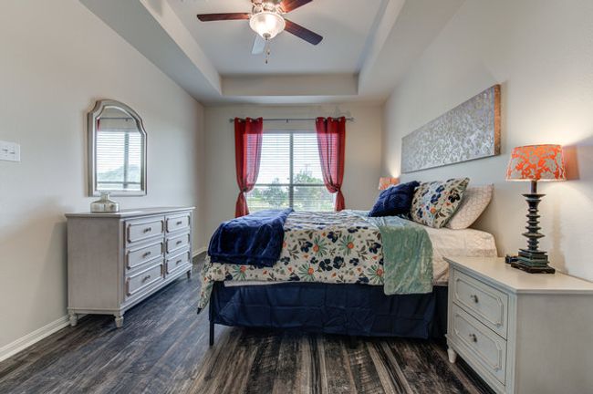 Bedroom featuring dark wood-style flooring, a tray ceiling, baseboards, and ceiling fan | Image 8