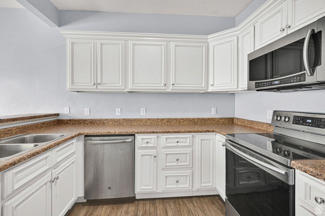 Kitchen with appliances with stainless steel finishes, white cabinetry, and wood finished floors | Image 7