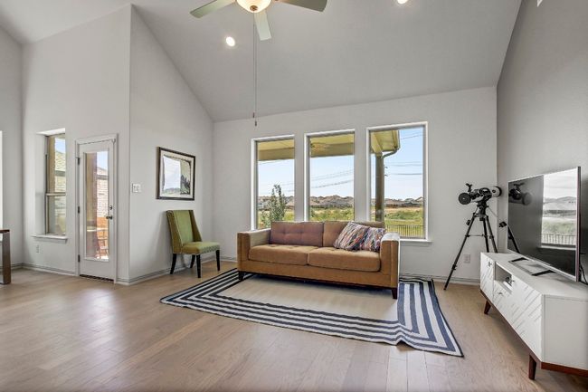 Living room with plenty of natural light, high vaulted ceiling, light wood-style floors, ceiling fan, and recessed lighting | Image 12