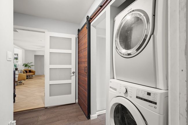Laundry room with stacked washer and dryer, a barn door, and dark wood-style floors | Image 34