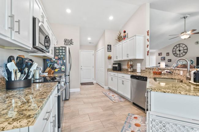 Kitchen featuring lofted ceiling, white cabinetry, appliances with stainless steel finishes, ceiling fan, and light stone countertops | Image 14