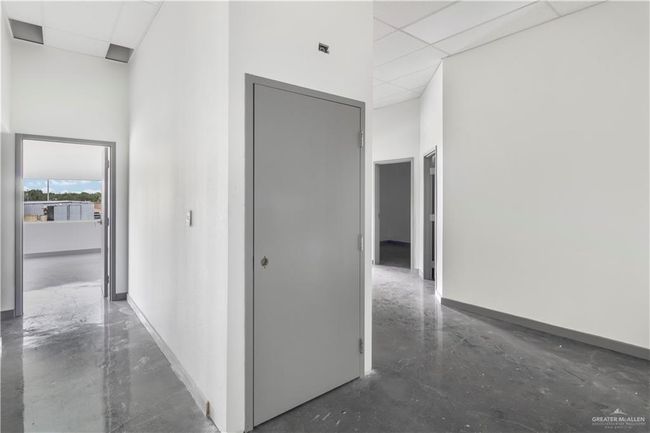 Hallway featuring a paneled ceiling, finished concrete flooring, a towering ceiling, and baseboards | Image 36