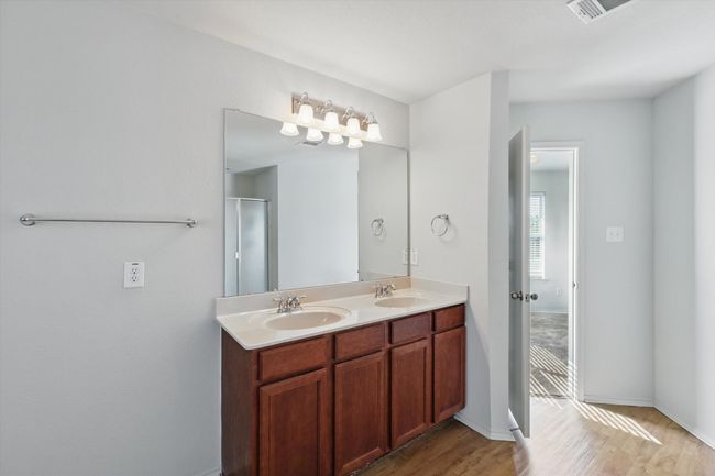 Full bath with wood finished floors, double vanity, a shower with door, and baseboards | Image 14