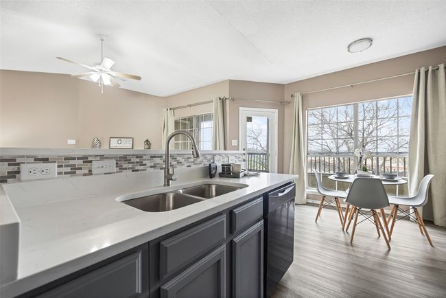Kitchen featuring sink, light stone counters, light wood-type flooring, black dishwasher, and backsplash | Image 6