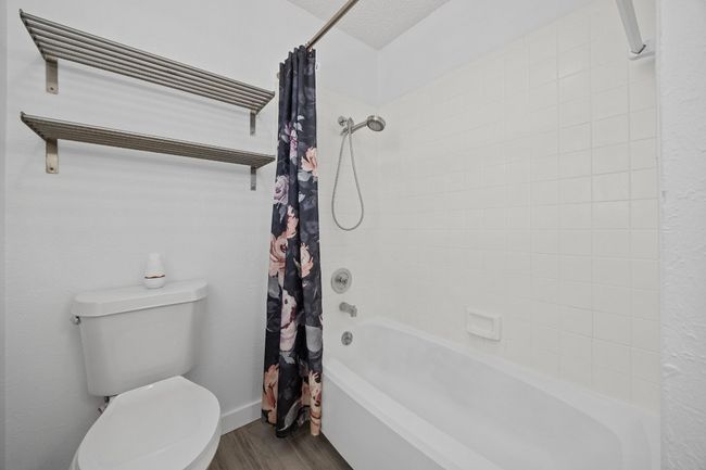 Bathroom featuring wood finished floors, toilet, and shower / tub combo with curtain | Image 19