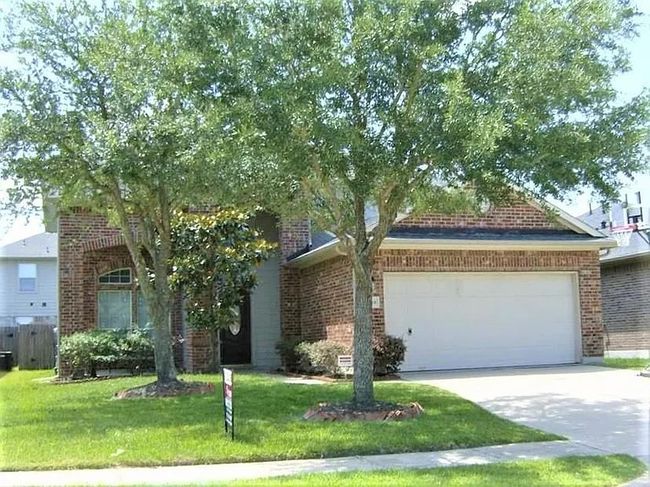 View of property hidden behind natural elements with brick siding, an attached garage, and driveway | Image 9