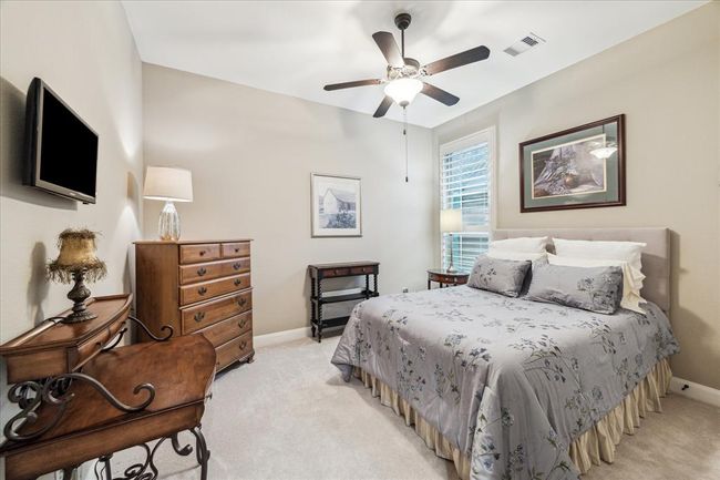 One of two secondary bedrooms on the main level featuring plantation shutters. | Image 20