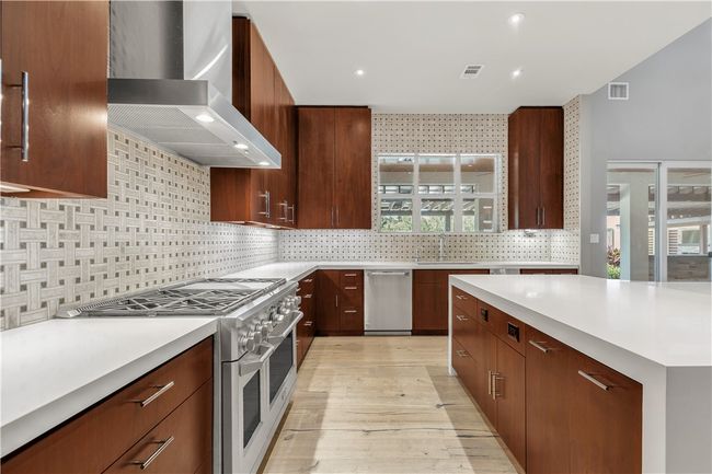 Kitchen with wall chimney exhaust hood, appliances with stainless steel finishes, light countertops, and recessed lighting | Image 10