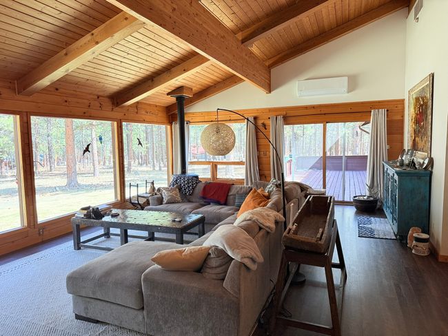 Living area with lofted ceiling with beams, wood finished floors, an AC wall unit, and wood ceiling | Image 6