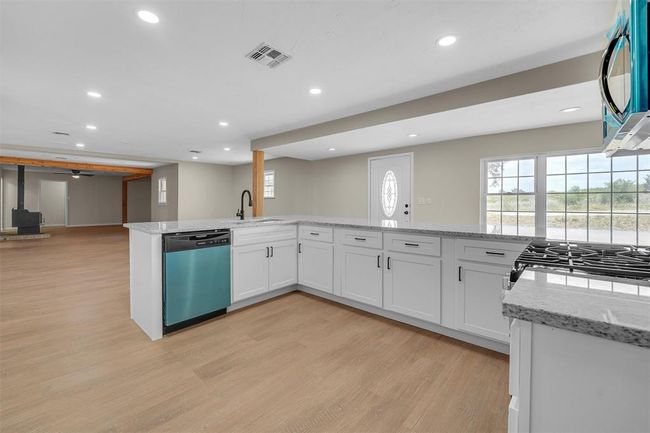 Kitchen featuring stainless steel appliances, sink, light stone counters, light hardwood / wood-style floors, and white cabinetry | Image 22