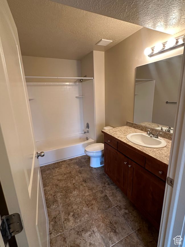 Bathroom with a textured ceiling, shower / bathing tub combination, vanity, and toilet | Image 13