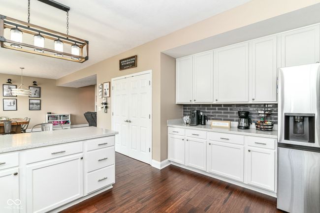 kitchen featuring stainless steel fridge with ice dispenser, dark wood-style floors, light countertops, and white cabinets | Image 9